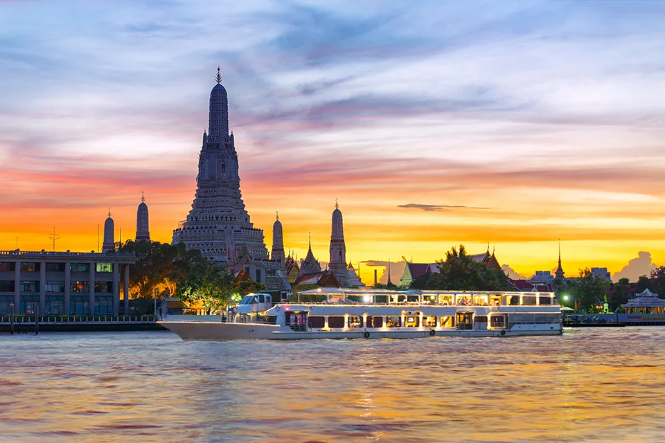 Evening cruise boat on Bangkok's Chao Phraya River offering spectacular sunset views of the iconic Temple of Dawn