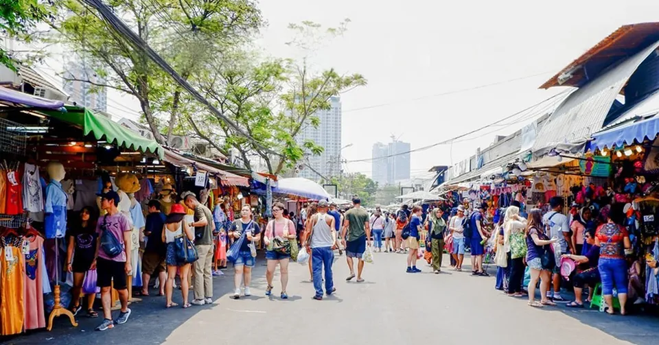 The lively atmosphere of Chatuchak Weekend Market showing tourists and locals browsing countless vendor stalls