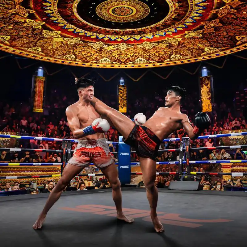 Top 10 Must-Do Activities in Bangkok: Muay Thai boxers exchange kicks during a match at Bangkok's historic Rajadamnern Stadium with its distinctive golden Thai-style ceiling