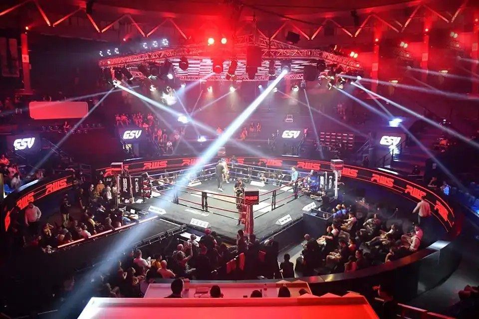 Top 10 Must-Do Activities in Bangkok: Spectators fill the arena watching fighters compete in the ring under bright spotlights and red stage lighting at Bangkok's Rajadamnern Stadium