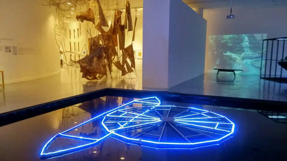 Reflective pool and glowing blue light at BACC’s contemporary exhibit—art meets atmosphere.