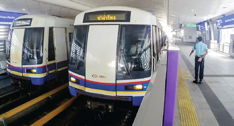 Bangkok's MRT subway train at a clean, modern station platform with a staff member standing nearby