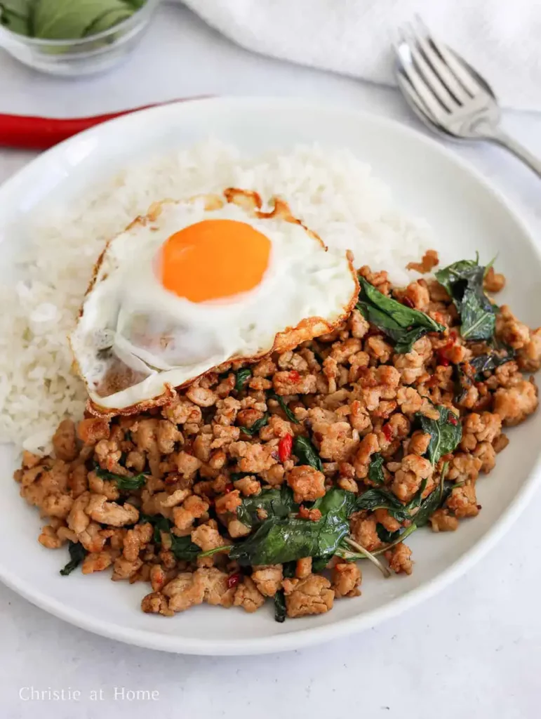 Bangkok FAQs: Pad Kra Pao served with rice and a crispy fried egg, bursting with chili, basil, and street food flavor.