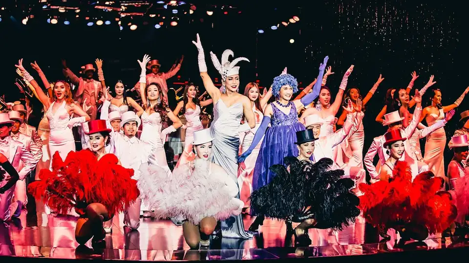 Glamorous Calypso performers in glittering outfits and feathered headpieces light up the stage.