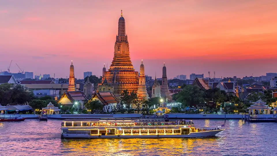 Dinner cruise glides past Wat Arun at sunset, with golden skies and temple lights.