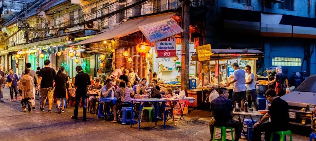 Evening street food scene in Bangkok with locals dining at vibrant roadside stalls.