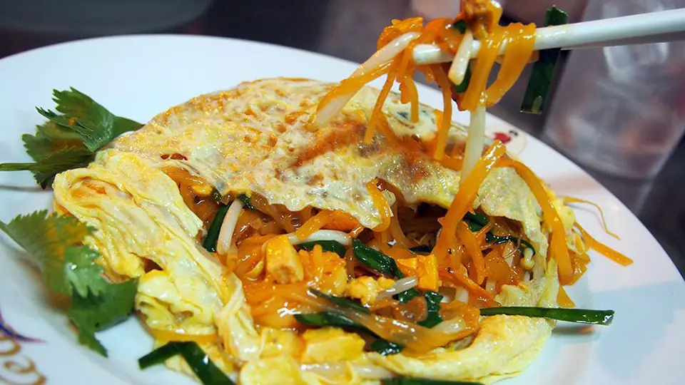 Top Bangkok Street Food: Thip Samai's signature Pad Thai wrapped in a delicate egg crepe with noodles being lifted by chopsticks