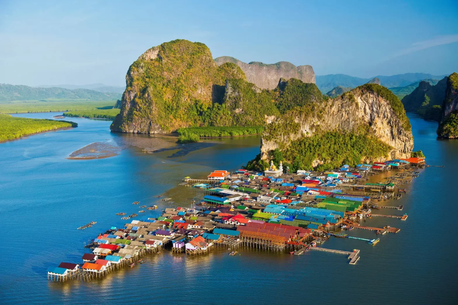 Stunning bird's-eye view of Ko Panyi's traditional sea gypsy village, with hundreds of brightly colored houses on wooden stilts nestled between massive limestone islands