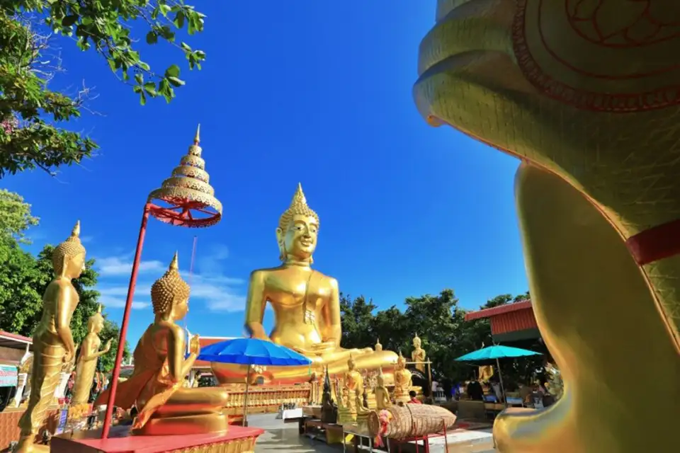 Golden Buddha statues at Big Buddha Pattaya temple, featuring a large seated Buddha surrounded by smaller figures under a bright blue sky