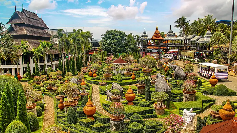 Family Trip in Pattaya: Elaborate landscaped gardens at Nong Nooch featuring geometric hedge patterns, traditional clay urns, and Thai-style buildings