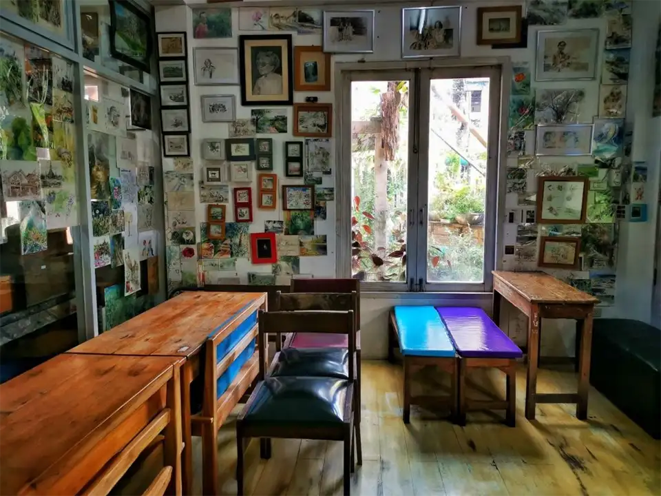 Family Trip in Pattaya: Inspiring interior of The Sketch Book Art Café showcasing hundreds of sketches and paintings covering every wall with cozy wooden seating