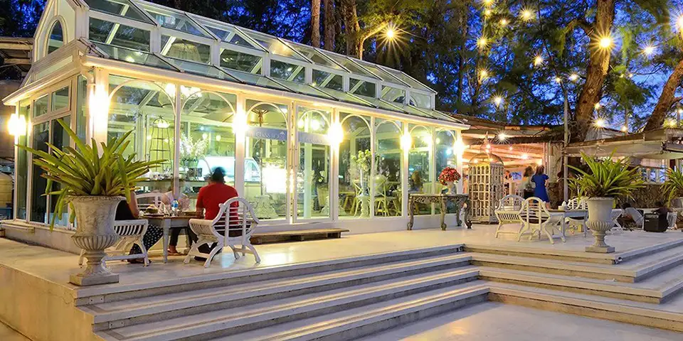 Family Trip in Pattaya: Romantic evening atmosphere at The Glass House restaurant in Pattaya, showcasing its distinctive Victorian greenhouse architecture with warm lighting