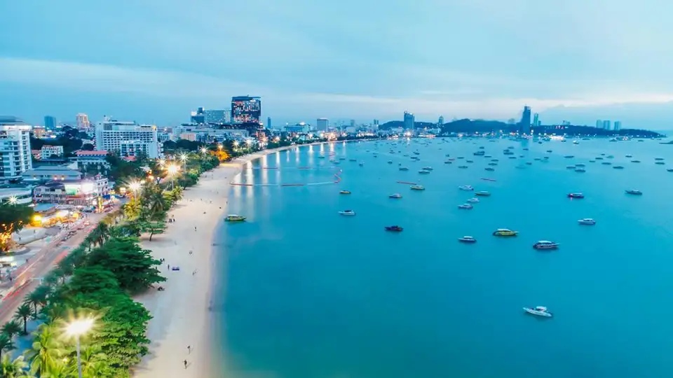 Family Trip in Pattaya: Evening panorama of Pattaya Bay with numerous boats moored in the calm blue waters and the illuminated beachfront