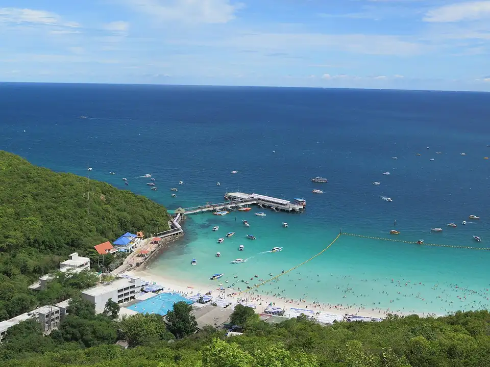 Family Trip in Pattaya: Beautiful bay at Koh Larn island showing white sand beach, swimming areas, and boats anchored in the clear blue water