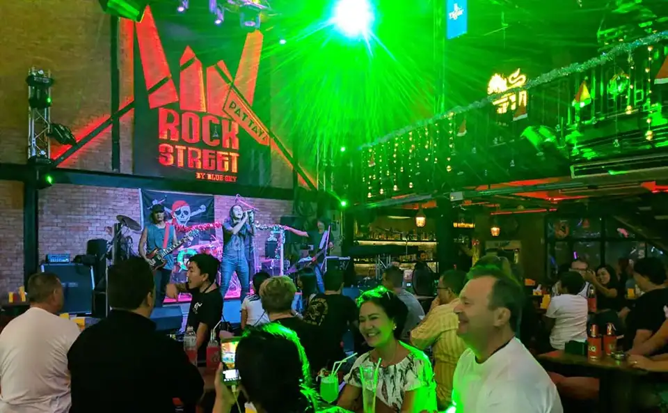 Live rock band performing at a vibrant bar on Walking Street Pattaya with neon lights and lively crowd.