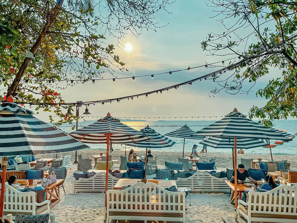 Beach club seating at The Glass House Boho in Pattaya with striped umbrellas and ocean views