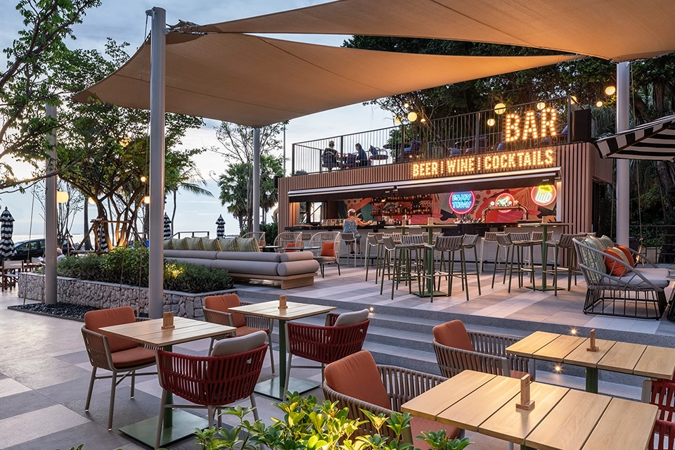 The Collective restaurant at Holiday Inn Pattaya Beach featuring contemporary dining tables and illuminated bar area with sea views