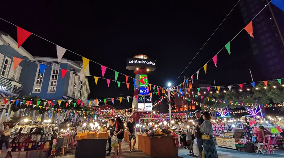 Colorful night market in Pattaya with food stalls, lights, and shoppers near Central Marina.