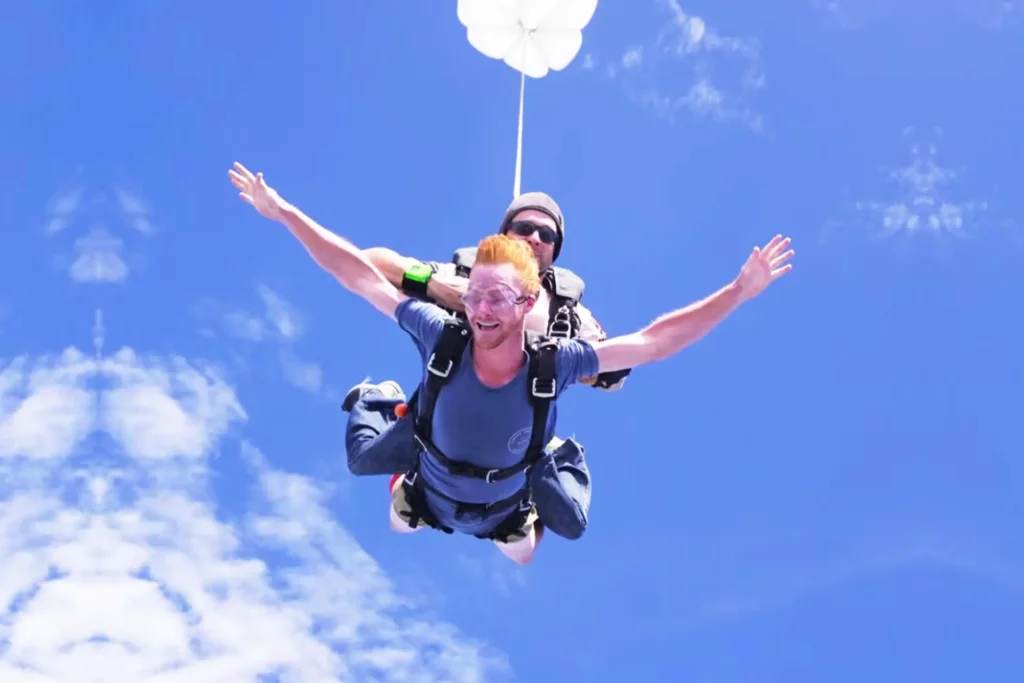 Tourist enjoying tandem skydiving over Pattaya with bright blue sky in the background.