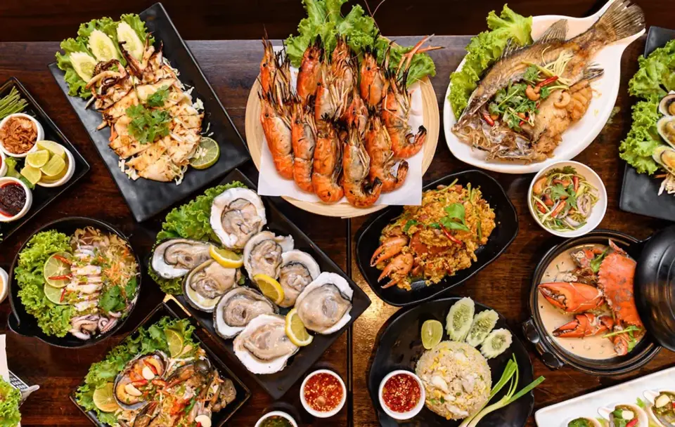 Delicious Thai seafood feast in Pattaya with grilled prawns, oysters, crab, and traditional dishes on the table.