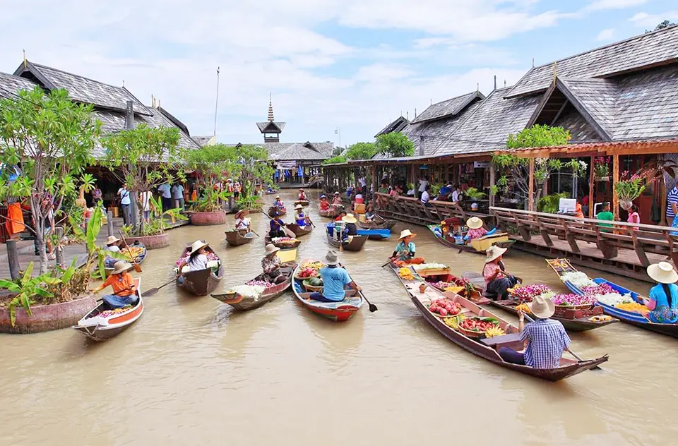 Pattaya photo spots: Colorful floating market scene in Pattaya with vendors in traditional boats selling fruits and vegetables from the water, surrounded by wooden Thai-style buildings