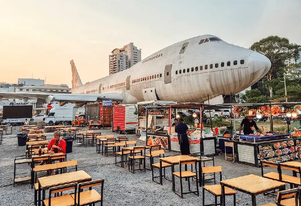 Cool airplane restaurant in Pattaya - diners enjoy street food at outdoor tables right next to an old jumbo jet that's been turned into part of the dining experience