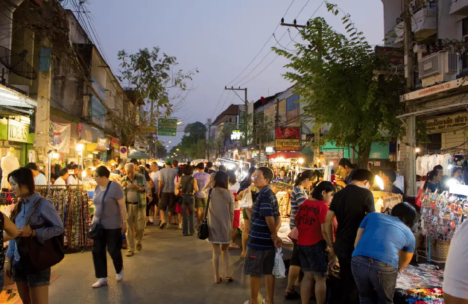 Lively evening atmosphere at a Pattaya street market at Soi Buakhao with locals and tourists walking between vendor stalls selling various goods under the streetlights