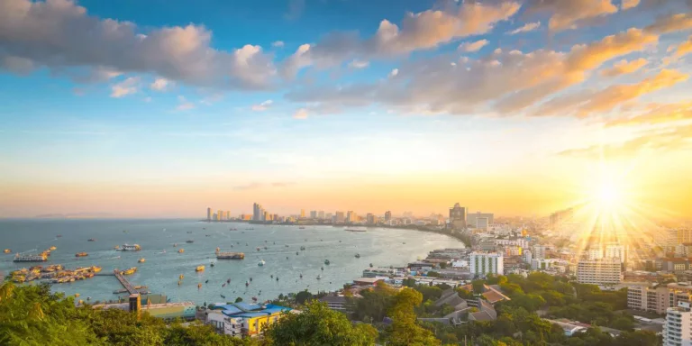Golden hour aerial shot of Pattaya beach with busy boat traffic in the bay and the city skyline in the background