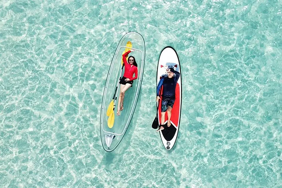 Beautiful aerial perspective of clear kayaking activity showing paddlers in see-through boats over shallow tropical waters