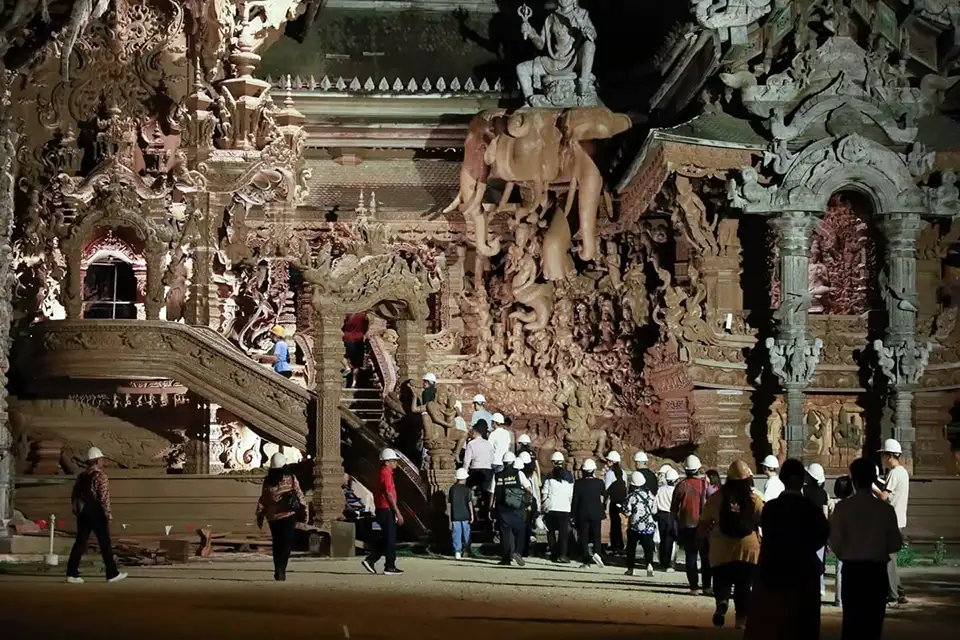 Visitors exploring the ornate interior of the Sanctuary of Truth in Pattaya, with detailed wooden carvings and sculptures covering every surface