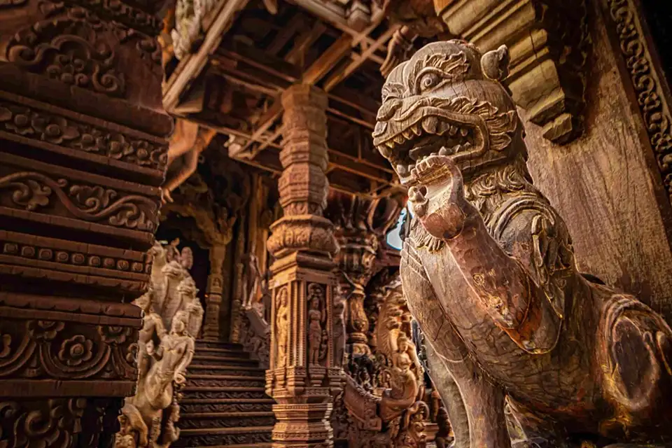 Intricate wooden dragon carvings and ornate pillars inside the Sanctuary of Truth temple, displaying masterful traditional craftsmanship