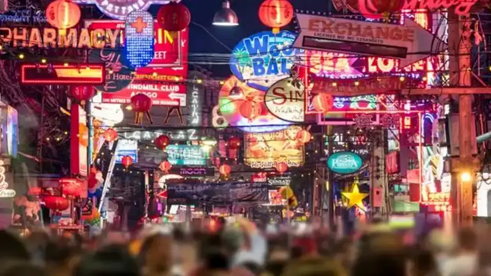 Pattaya photo spots: Bustling Walking Street in Pattaya at night, filled with colorful neon bar signs, red lanterns, and crowds of people enjoying the nightlife