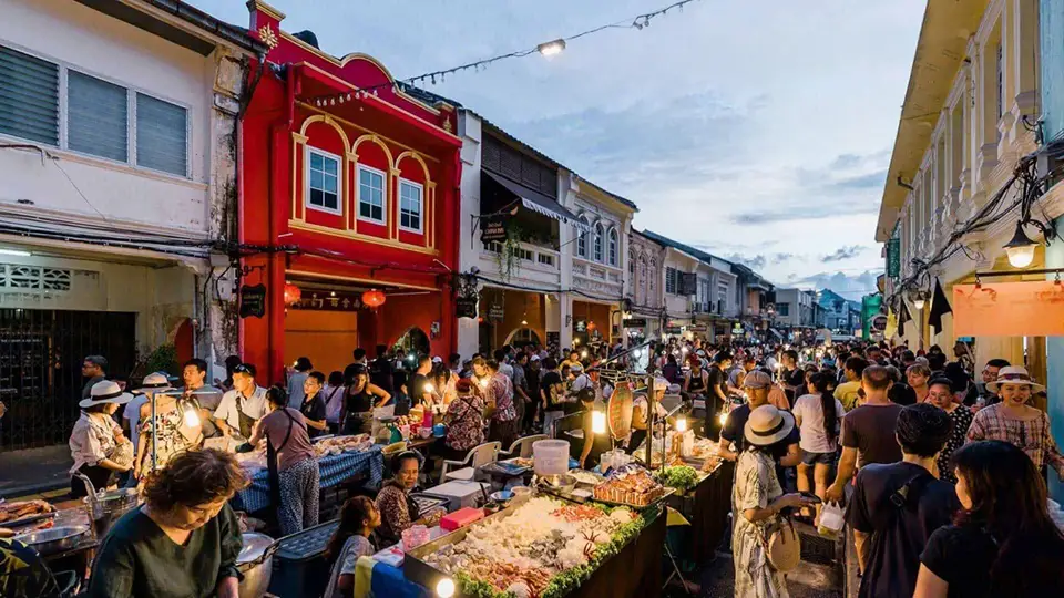Bustling evening street market in Phuket's Old Town with crowds browsing local vendors along colorful Sino-Portuguese shophouses