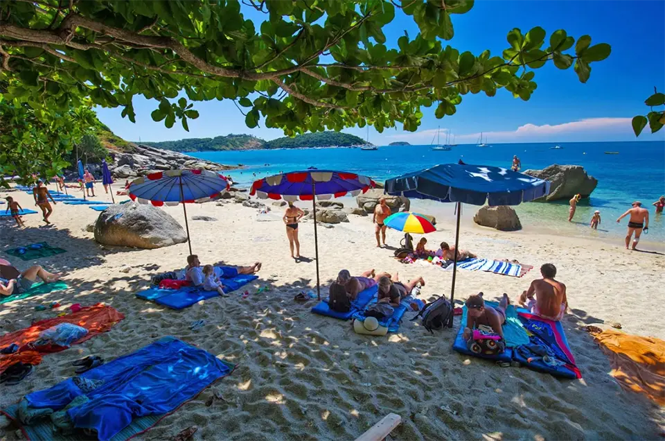 Hidden Beaches in Phuket: Relaxing day at Ao Sane Beach in Phuket with umbrellas, families, and clear blue water.