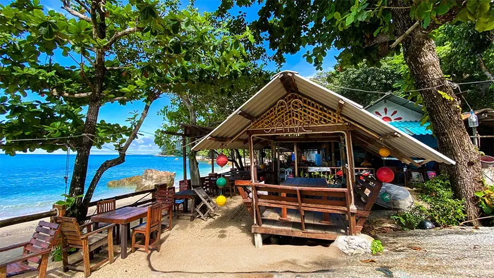 Hidden Beaches in Phuket: Cozy beachfront restaurant at Ao Sane Beach in Phuket surrounded by trees and sea views.