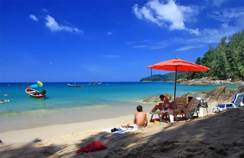 Hidden Beaches in Phuket: Relaxing on Banana Beach in Phuket with clear blue sea, umbrellas, and longtail boats.