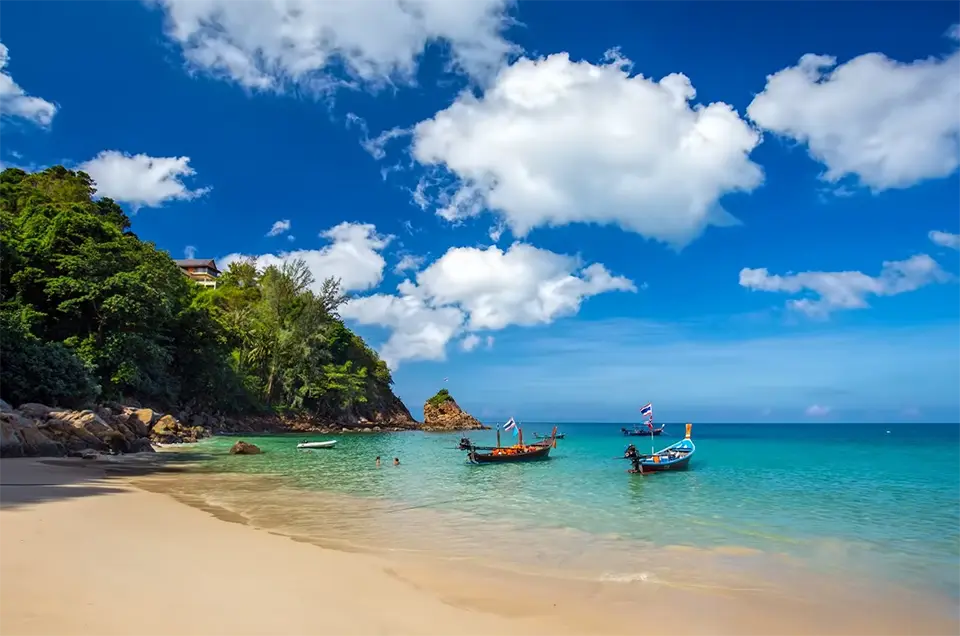 Hidden Beaches in Phuket: Scenic view of Banana Beach in Phuket with turquoise water, white sand, and longtail boats.
