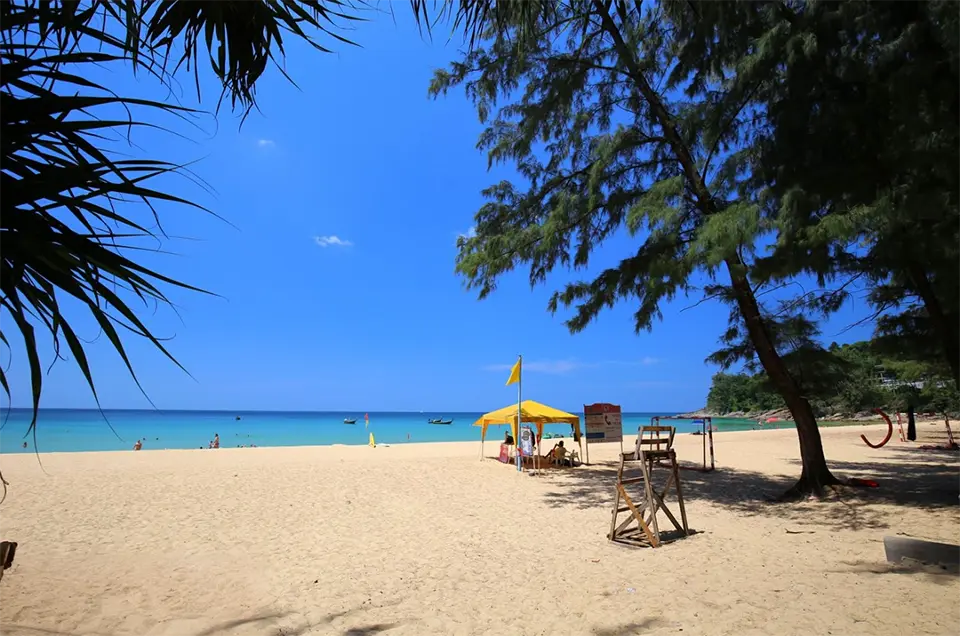 Hidden Beaches in Phuket: Sunny day at Nai Thon Beach in Phuket with golden sand, clear blue sea, and shady trees.