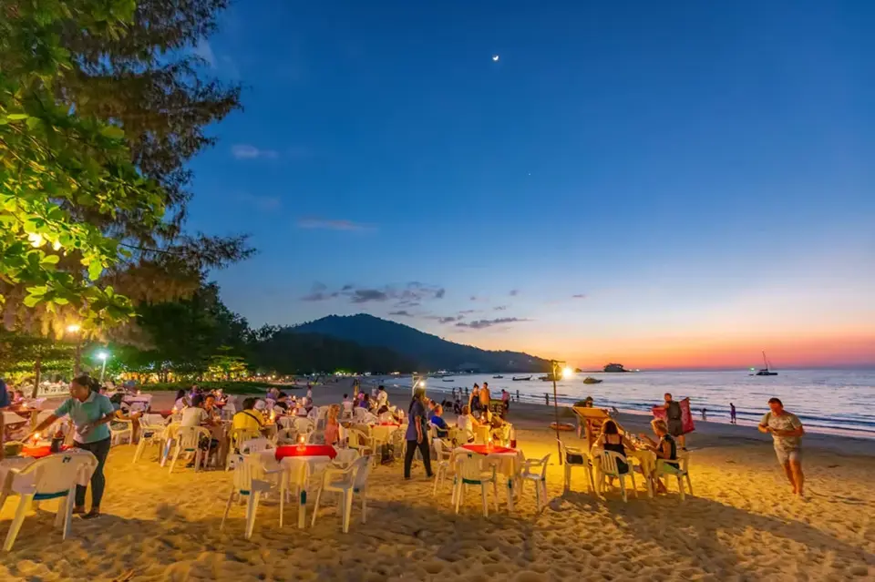 Hidden Beaches in Phuket: Beachfront dining at Nai Yang Beach in Phuket during a colorful sunset.