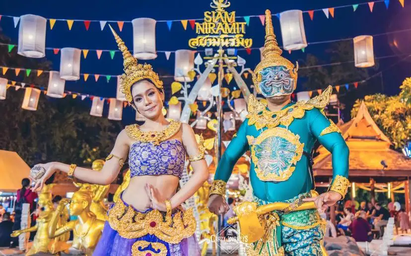 Phuket Cultural Shows: Smiling performers in ornate Thai traditional costume with golden headdress and colorful wings dances on stage at Phuket FantaSea