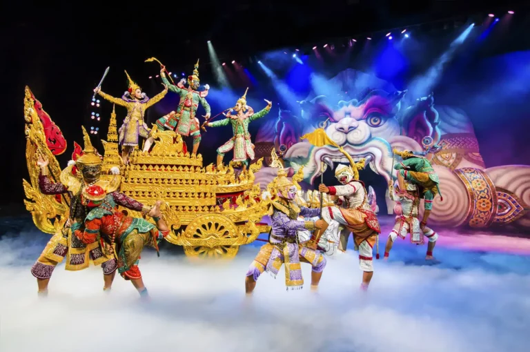 Phuket Cultural Shows: Colorful Thai cultural performance featuring dancers in elaborate traditional costumes with masks and golden ornaments, performing around a decorated golden chariot on a theatrical stage