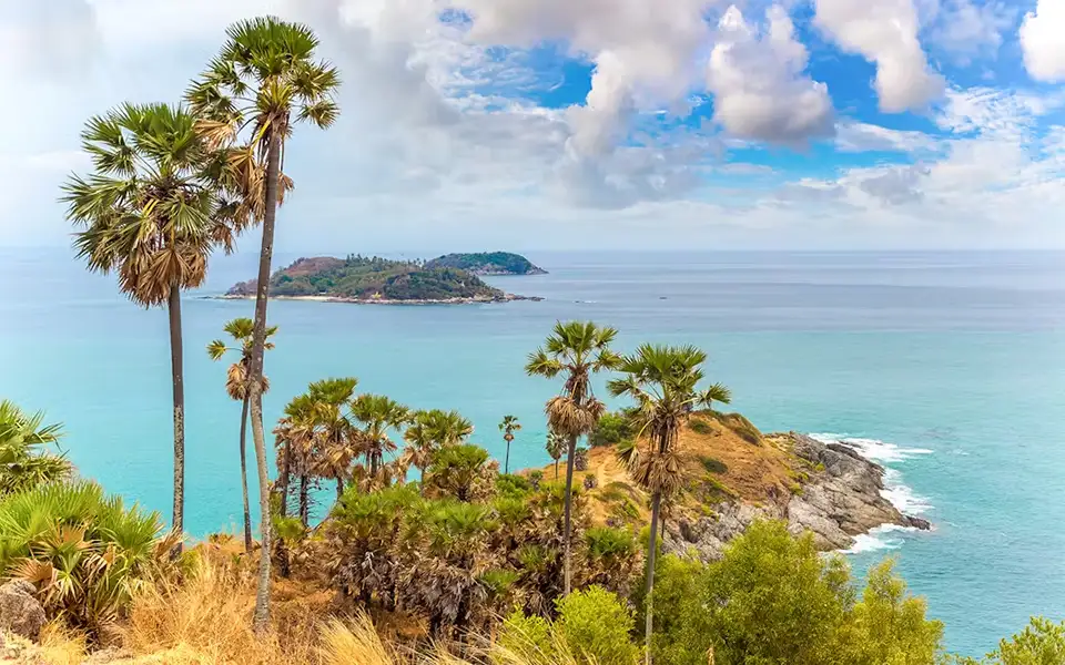 Top Photo Spots in Phuket: Breathtaking panoramic view from Promthep Cape showing turquoise waters, rocky coastline, and tropical palm trees
