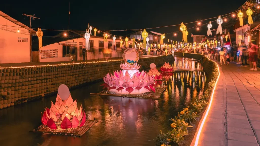 Giant illuminated lotus krathongs floating on canal during Loy Krathong festival at night