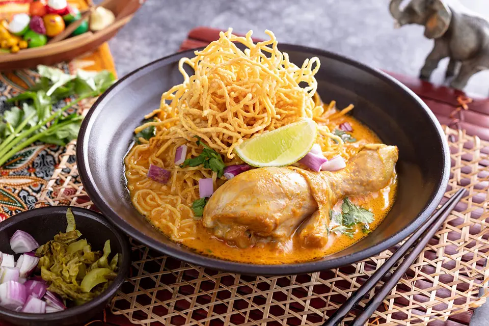 Thai food: Traditional Northern Thai Khao Soi featuring egg noodles, tender chicken in coconut curry broth, topped with crispy noodles