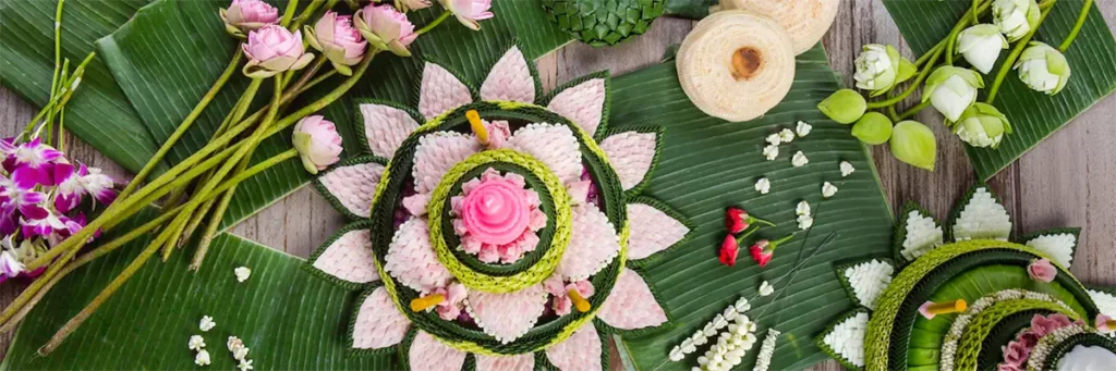 Handcrafted krathong made from banana leaves shaped like a lotus flower with pink decorations and fresh flowers