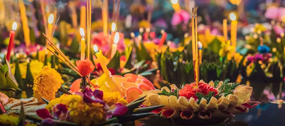Colorful krathongs with flowers and candles floating on water during Loy Krathong festival