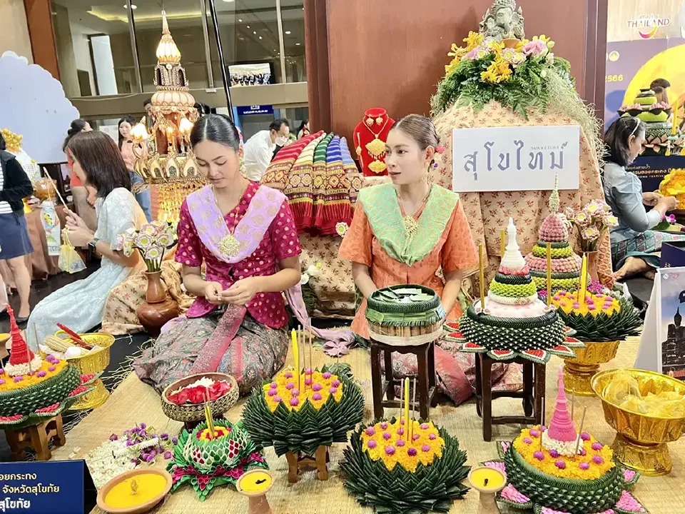 Krathong-making demonstration with elaborately decorated banana leaf floats and women in traditional Thai costumes