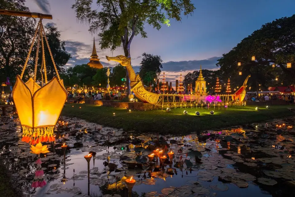 Loy Krathong festival at Sukhothai with elaborate golden swan boats, glowing lanterns, and krathongs floating at dusk