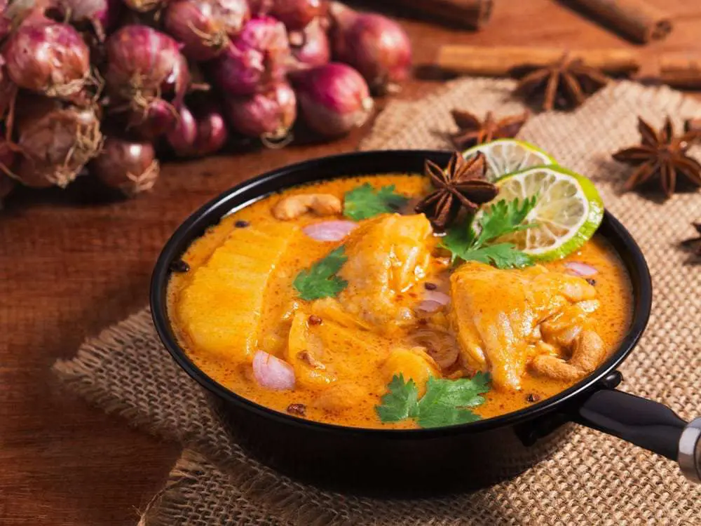 Thai food: Massaman curry with beef and potatoes in a black pan, garnished with lime and cilantro