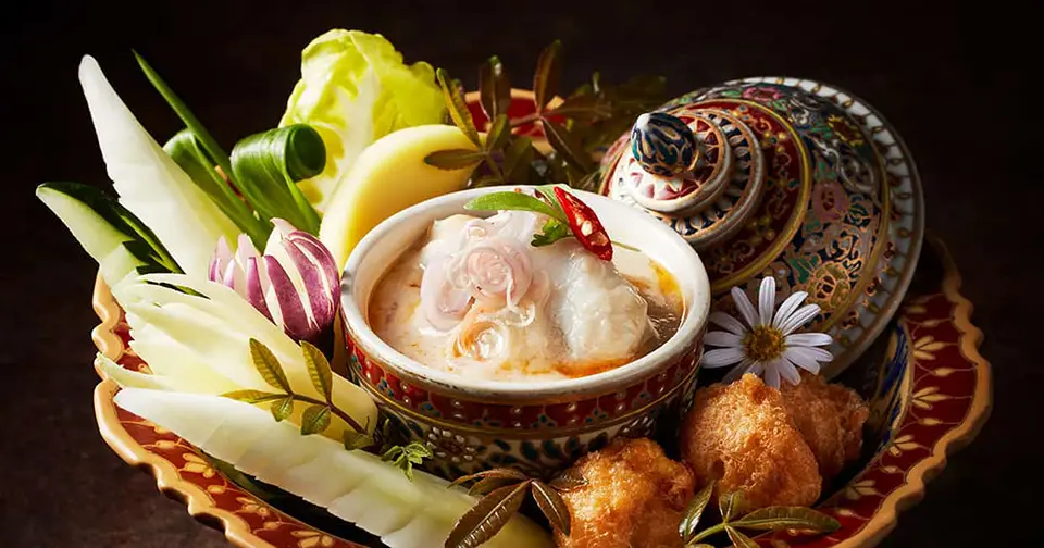 Thailand Luxury Getaway: Refined Thai soup served in traditional porcelain with intricate vegetable carvings and fried dumplings